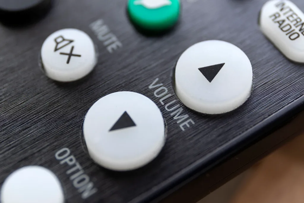 Very close up look at the volume up and down buttons on a standard television TV remote control.